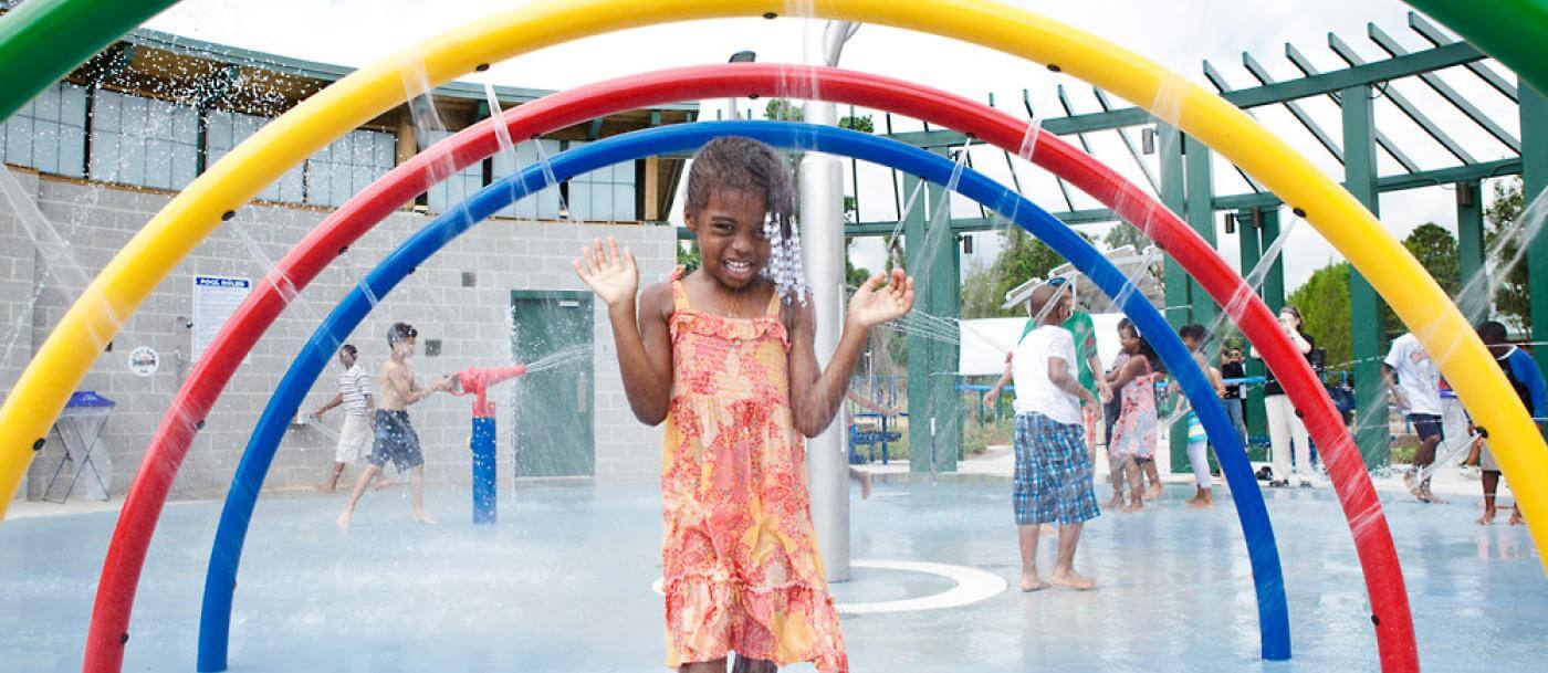 A child is playing in a water park with colorful sprinklers.