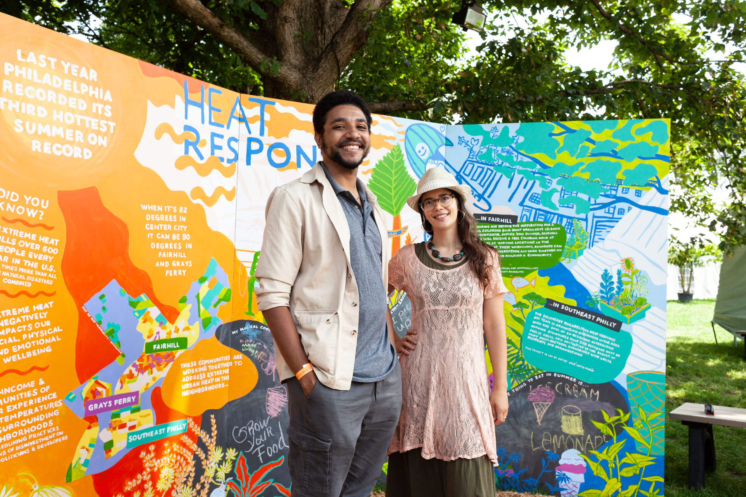 A man and woman standing in front of a colorful poster.
