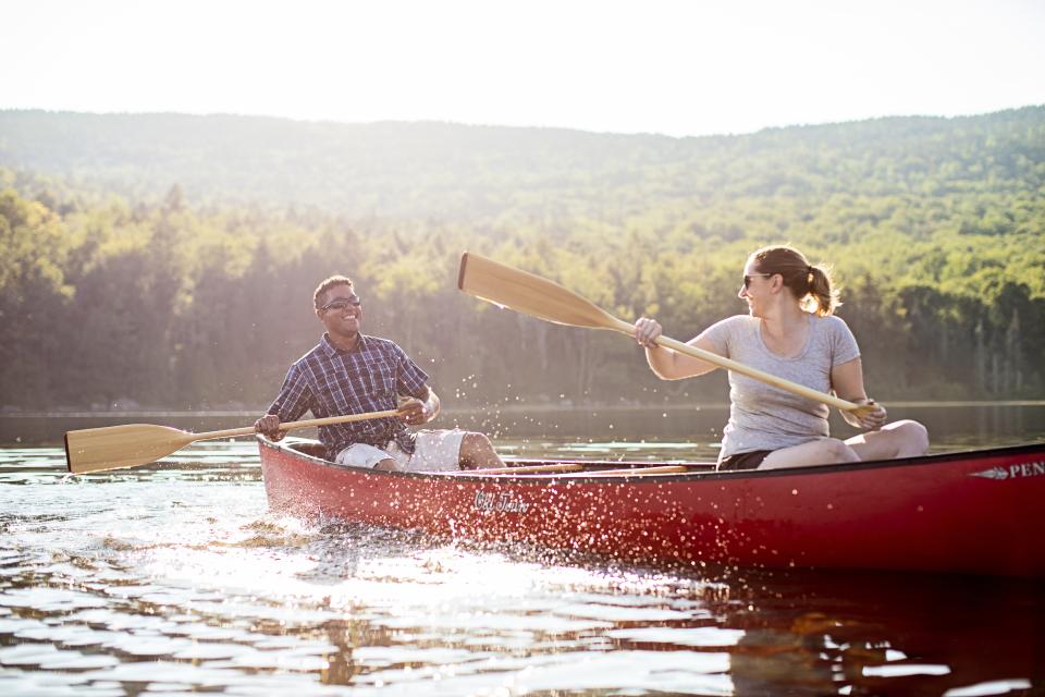 A man and woman paddling a canoe on a lake.
