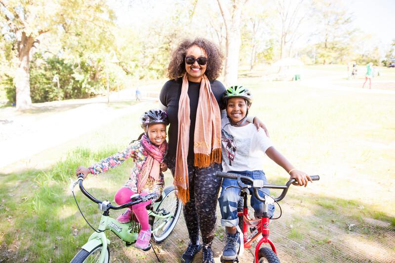 A woman and her children are posing with their bicycles in a park.