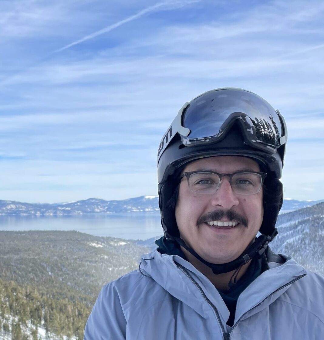 A man wearing a ski helmet on top of a mountain.