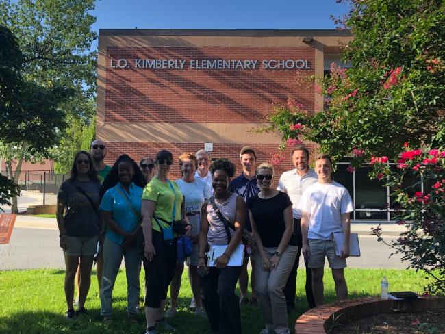 10 people smile for the camera in front of Kimberly Elementary School