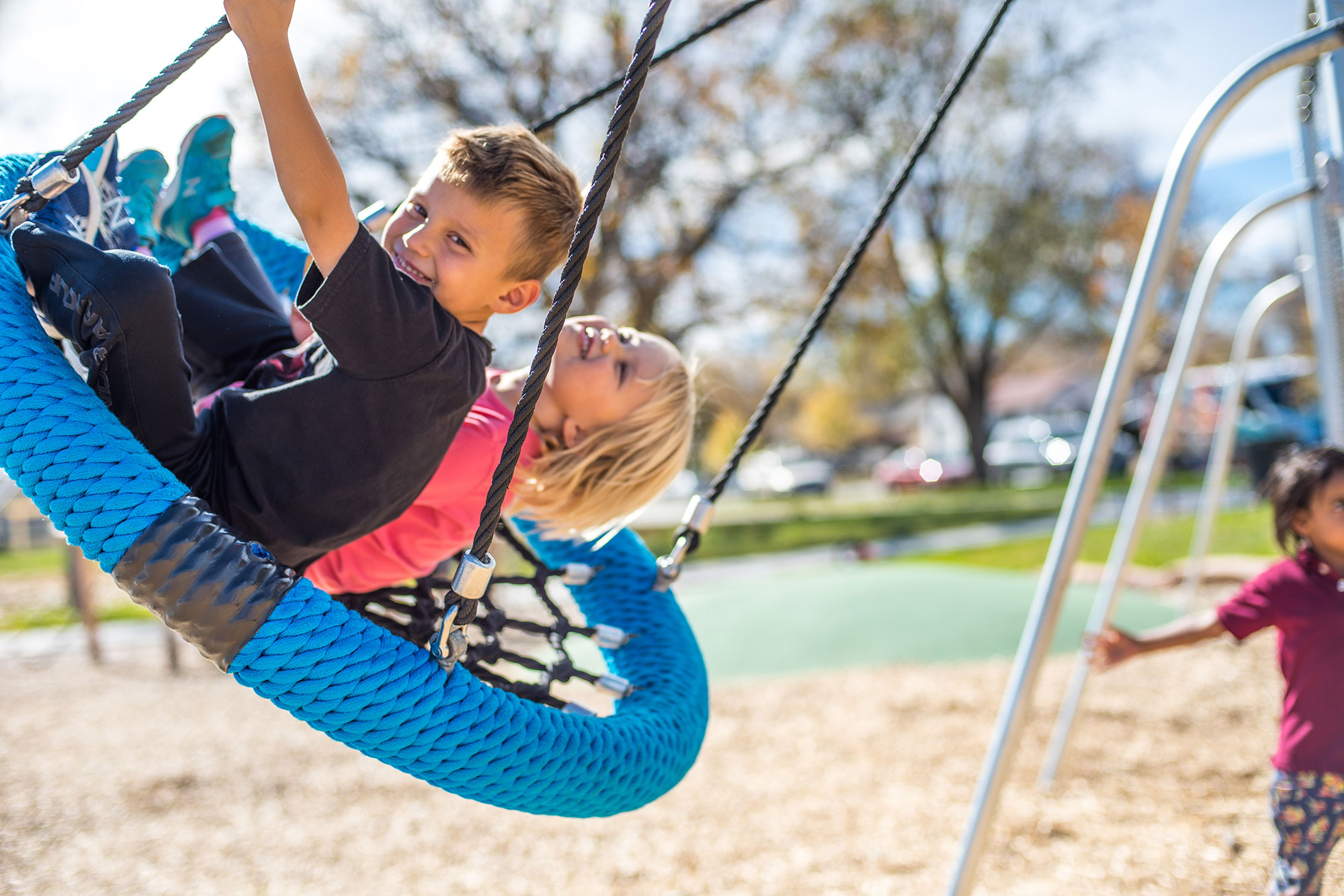 Two children playing on a swing at a playground.