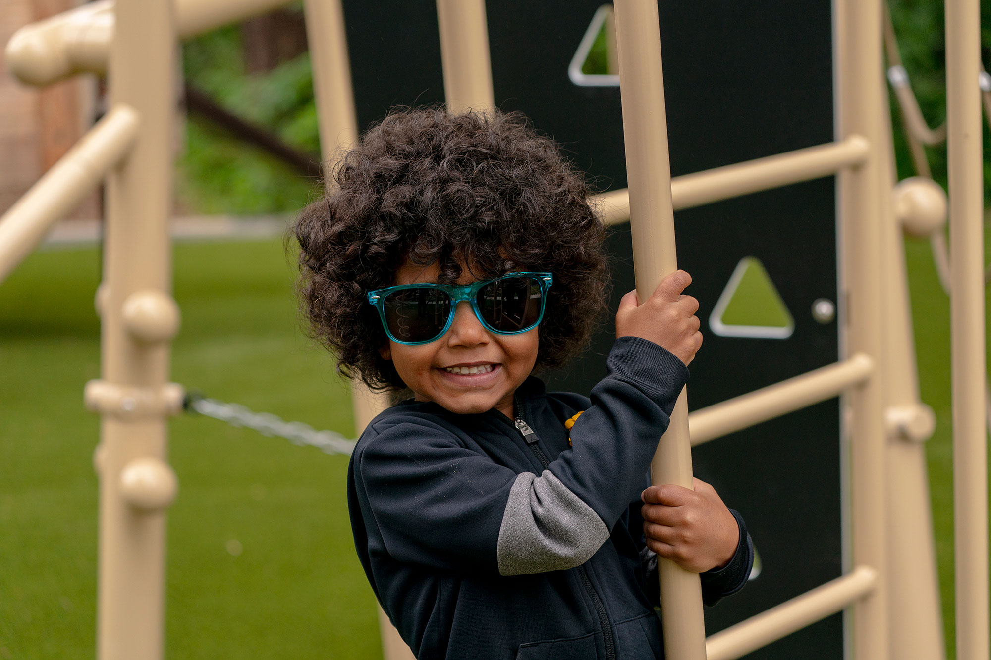 A young boy wearing sunglasses on a playground.