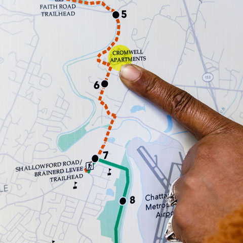 A person is pointing to a map of a trail.