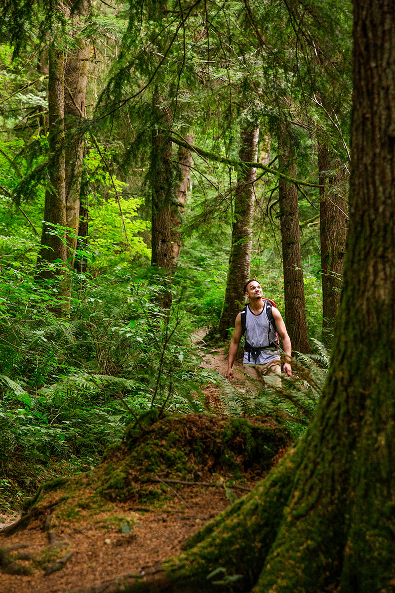 A man hiking through a forest in a backpack.