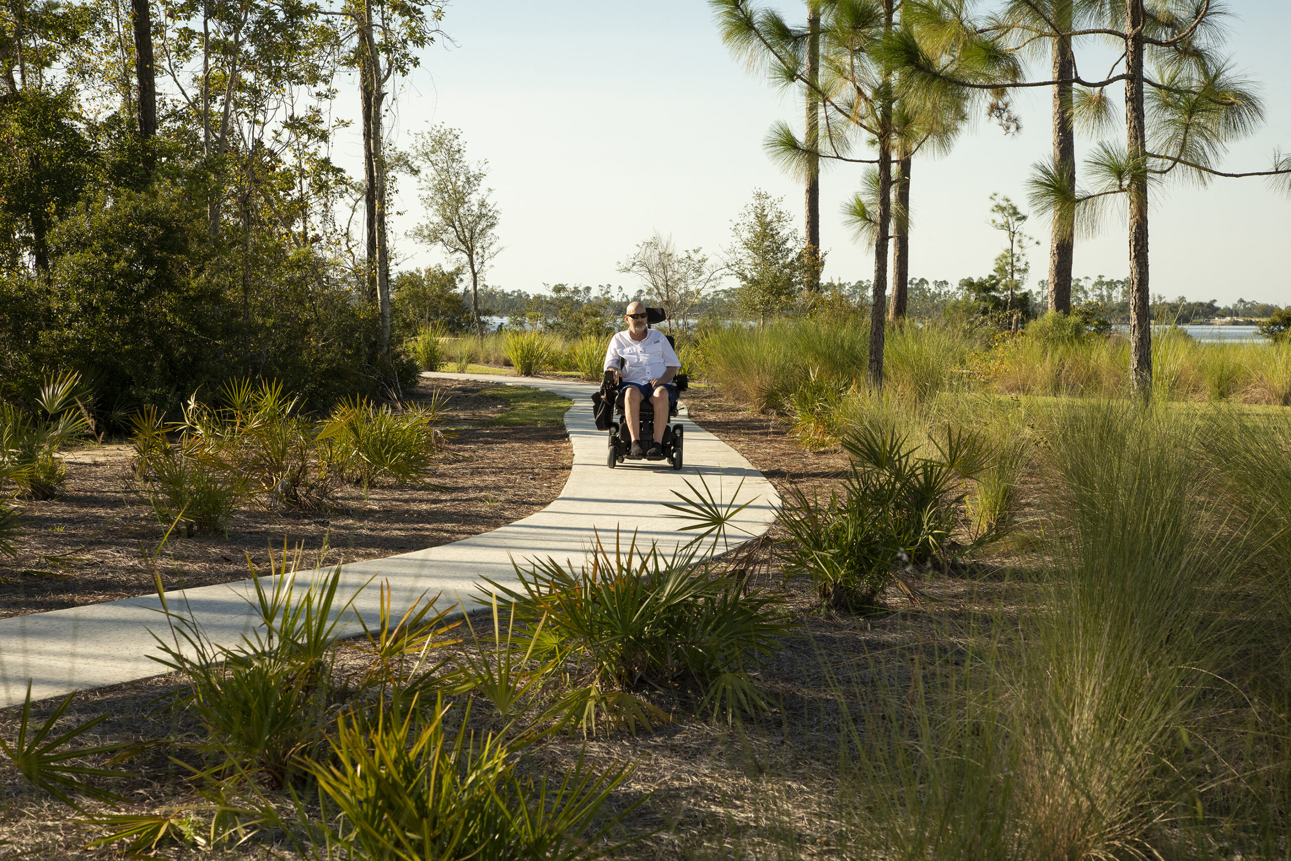 A man using a motorized wheelchair enjoys exploring Lynn Haven Park via the paved, accessible path.